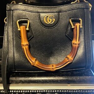 All black handbag with bamboo handles and a cross body strap.